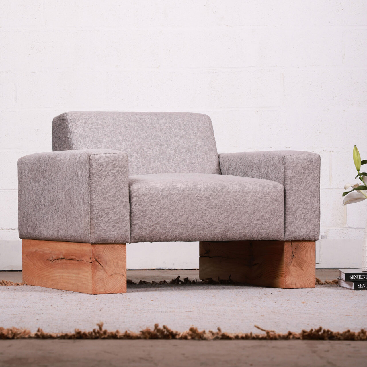 The Beam luxury Sofa by SENTIENT Furniture, with its clean lines and pale grey upholstery, sits on a solid wooden base, offering a modern, plush seating solution against a neutral background.