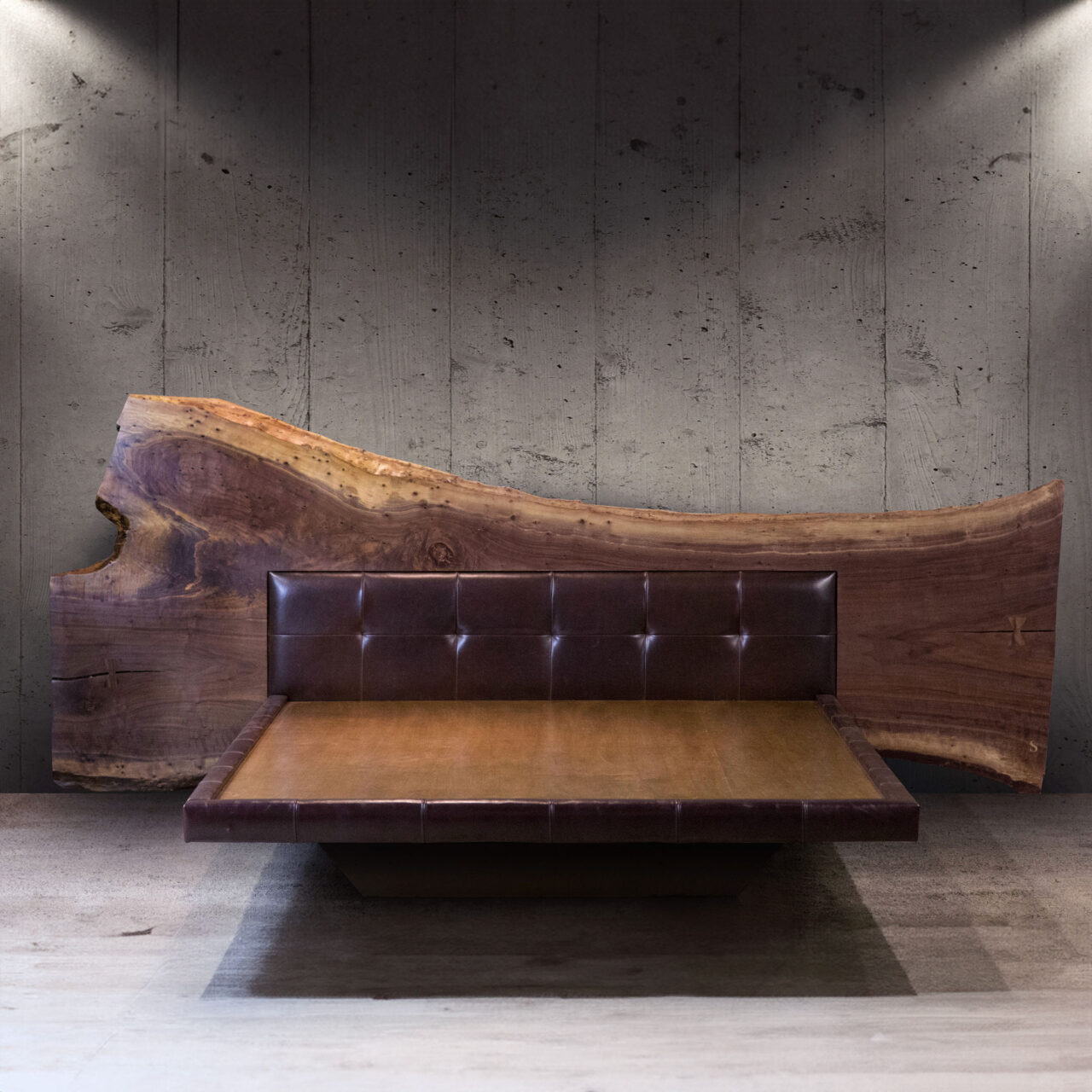 SENTIENT Furniture's luxurious live-edge bed with a smooth walnut backrest seamlessly transitioning from raw edge to polished, juxtaposed against a textured concrete wall.