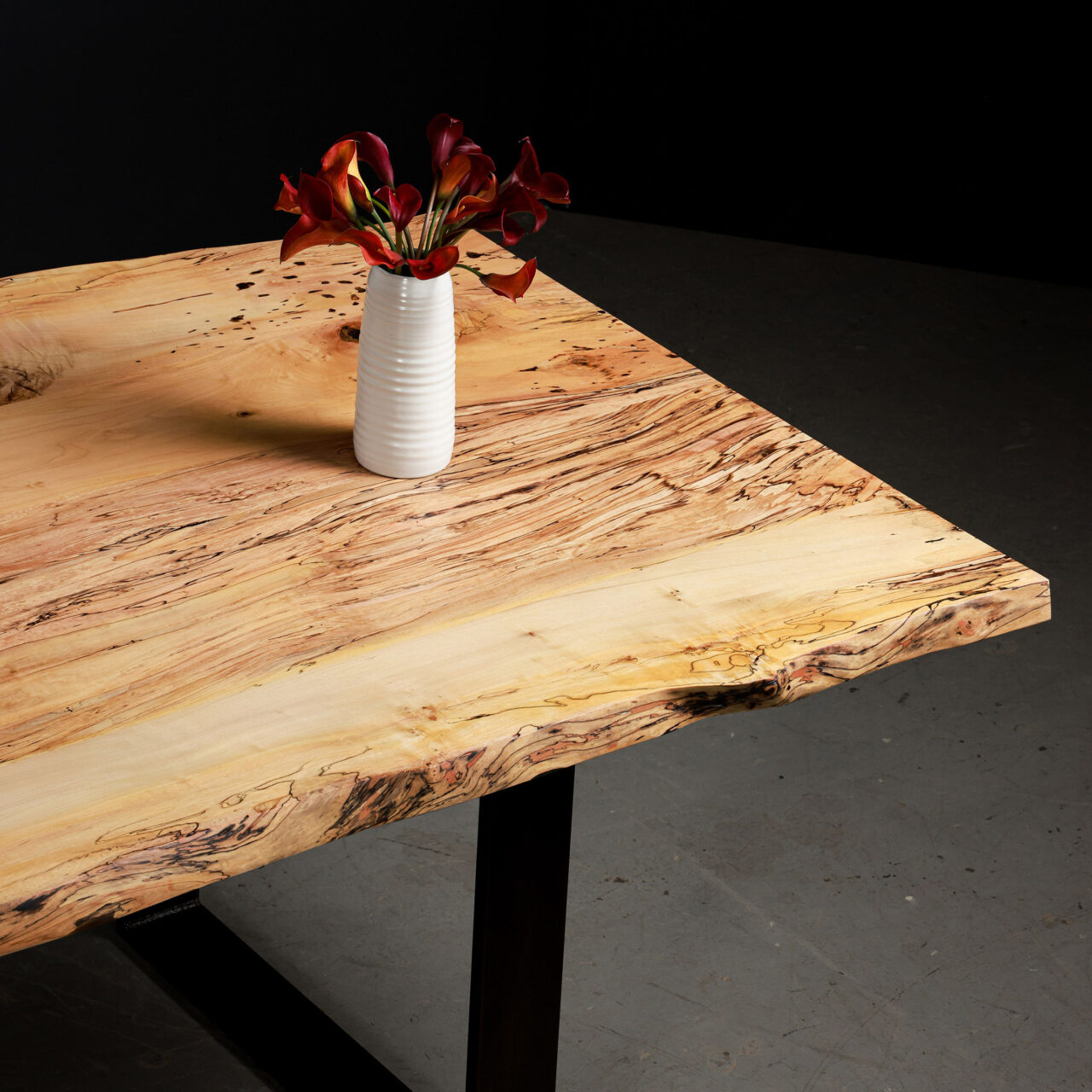 Custom live edge table in spalted maple, with black metal frame legs, and a white vase on top