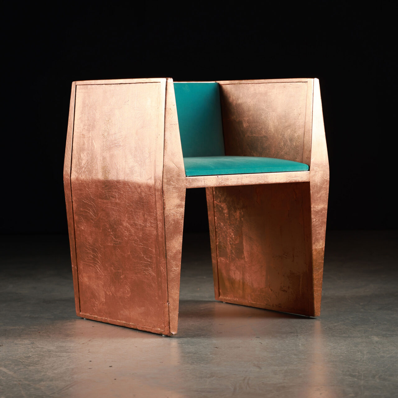 Wooden unique chairs - The SENTIENT Sapience copper chair, presented here from a fresh perspective, highlights the chair's angular construction and the rich texture of the copper. The teal cushion appears even more vibrant against the metallic sheen, emphasizing the chair's fusion of comfort and avant-garde style.
